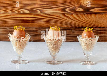 Mimosa decorated eggs in the nests in crystal glasses, idea of Easter decoration Stock Photo