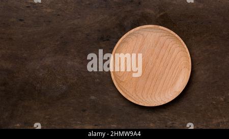 empty wooden plate on a dark wood surface, food or product photography background or backdrop, top view with copy space Stock Photo