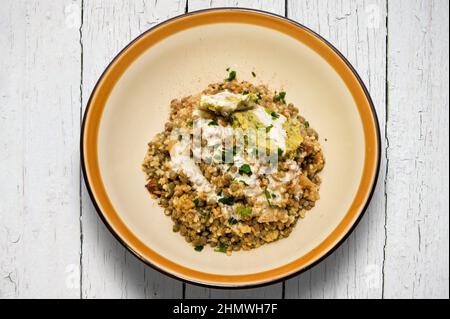 Mejadra, Mujaddara: dish from the Jewish tradition of the Middle East with rice, lentils, spices and crunchy onion. in colored earthenware dish on whi Stock Photo