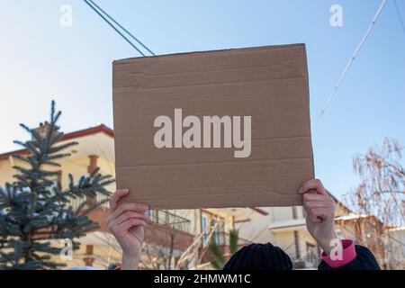 Woman holding blank cardboard box, protesting something. Copy space for text on cardboard box. Stock Photo