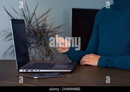 Young woman holding bank credit card and using laptop to buy on the internet, online shopping concept at home Stock Photo