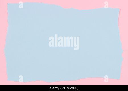 Grunge ripped light blue color paper page with ragged edge on pastel pink paper background. Top view Stock Photo