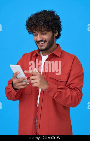 Happy indian young man using cell phone isolated on blue background. Stock Photo