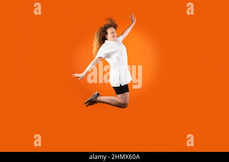 The young redhead woman in football uniform isolated jumping very high as a flight to the sun, fan human emotions concept. Stock Photo