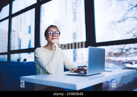 Smiling woman with hand at chin using laptop Stock Photo
