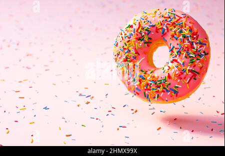 Colorful sprinkled pink donut on pink background Stock Photo