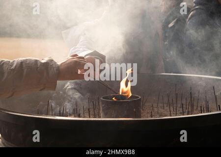 Incense light japanese temple in winter with smoke and people praying, flames burning in sand incense pot. Asian culture, asian religions, japanese Stock Photo