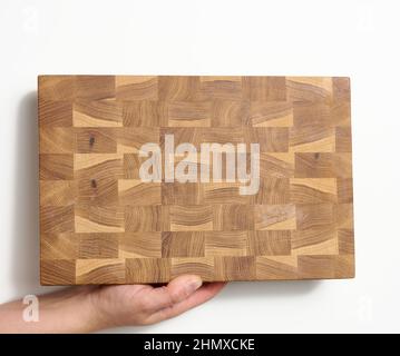 female hands hold empty rectangular brown wooden chopping board on white background Stock Photo