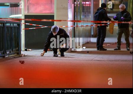 Hamburg, Germany. 12th Feb, 2022. Forensic technicians investigate at the cordoned-off scene of the injured man in front of a shopping center. In a knife attack in Hamburg-Harburg, a man was injured 'not insignificantly' according to police. The homicide squad is investigating, said a spokesman for the police situation center after the crime on Saturday evening. Credit: Jonas Walzberg/dpa/Alamy Live News Stock Photo