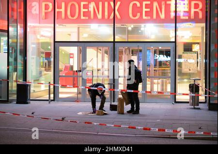 Hamburg, Germany. 12th Feb, 2022. Forensic technicians investigate at the cordoned-off scene of the injured man in front of a shopping center. In a knife attack in Hamburg-Harburg, a man was injured 'not insignificantly' according to police. The homicide squad is investigating, said a spokesman for the police situation center after the crime on Saturday evening. Credit: Jonas Walzberg/dpa/Alamy Live News Stock Photo