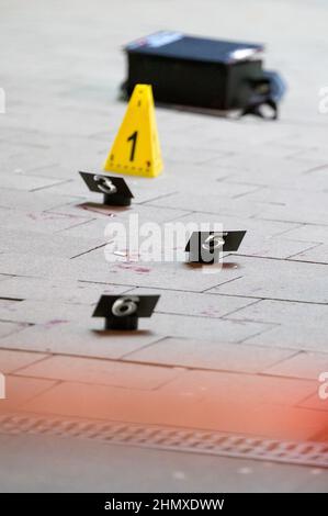 Hamburg, Germany. 12th Feb, 2022. Numbered evidence boards stand next to traces of blood at the cordoned-off site where the injured man was found in front of a shopping center. According to police, a man was 'not insignificantly' injured in a knife attack in Hamburg-Harburg. The homicide squad is investigating, said a spokesman for the police situation center after the crime on Saturday evening. Credit: Jonas Walzberg/dpa/Alamy Live News Stock Photo