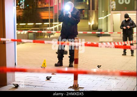 Hamburg, Germany. 12th Feb, 2022. Forensic technicians investigate at the cordoned-off scene of the injured man in front of a shopping center. In a knife attack in Hamburg-Harburg, a man was injured 'not insignificantly' according to police. The homicide squad is investigating, said a spokesman for the police situation center after the crime on Saturday evening. Credit: Jonas Walzberg/dpa/Alamy Live News Stock Photo