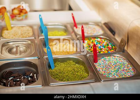 Fresh Fried Donuts sugary sprinkles toppings for donuts in a cafe on the street Stock Photo