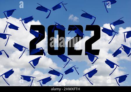 Blue graduation caps airborne in summer sky with 2022 text Stock Photo