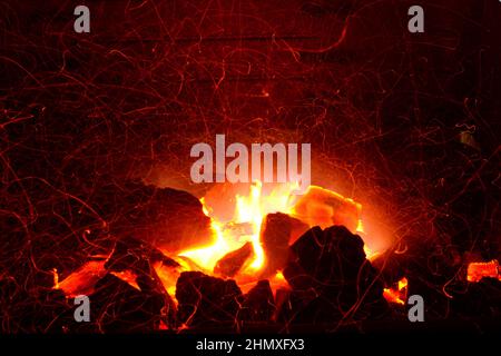 Embers of coal burning.Orange flames blaze in the fire. Bright orange grid nature brand. Burning embers of hot red color. The glowing embers of the co Stock Photo