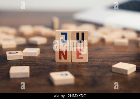 The name of the month June written on wooden cubes od the tabletop of th computer desk. High quality photo Stock Photo