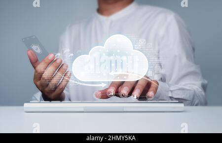 Cloud storage icon with businessman working with computer and glass phone. Cloud computing, technology, service, and connectivity concepts. Data prote Stock Photo