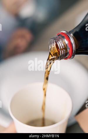 Pouring soda drink from bottle to glass, close up. Stock Photo
