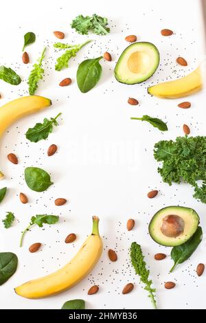 Vertical shot of bananas, avocados, almonds, and kale sticks on a white surface with space for text Stock Photo