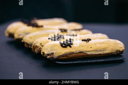 Close-up of eclairs in yellow glaze on a black background. Stock Photo