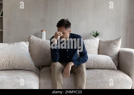 Tired frustrated young man feeling exhausted, suffering from migraine Stock Photo