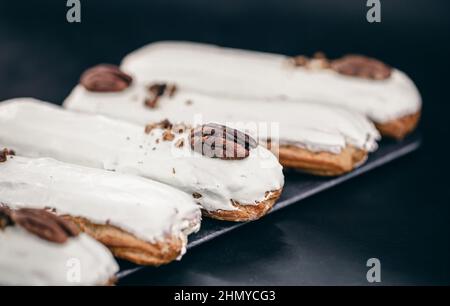 Close-up of eclairs in white glaze with pecans. Stock Photo