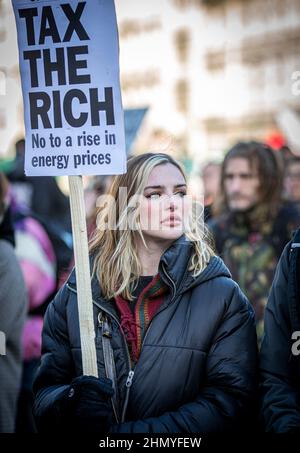 Young woman protest against the rises in fuel prices and costs of living holding a sign Tax The Rich in London . Stock Photo