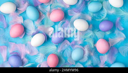 Eggs of different colors and feathers on a blue background. Festive Easter background. Stock Photo