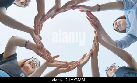 Friends make a circle with their palms against the blue sky. Stock Photo