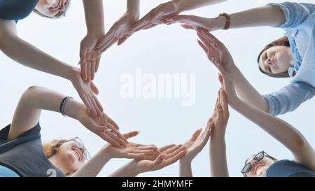 Friends make a circle with their palms against the blue sky. Stock Photo