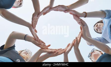 Friends make a circle with their palms against the blue sky. Stock Photo