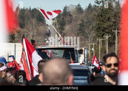 Vancouver, British Columbia, Canada. 12th Feb, 2022. A protestor waves on supporters, lined up for more than two kilometres to the US border in Surrey, B.C., Feb 12. The action comes as protests against provincial and national COVID-19 mandates erupt across the country. Thousands of supporters gathered on 8th Avenue and the 176 Street Pacific Highway intersection in Surrey to welcome a small convoy of protest vehicles travelling from nearby Chilliwack to the border crossing used primarily by truckers. Police tried to shutdown protesters' access, but their barricades were breached on sever Stock Photo