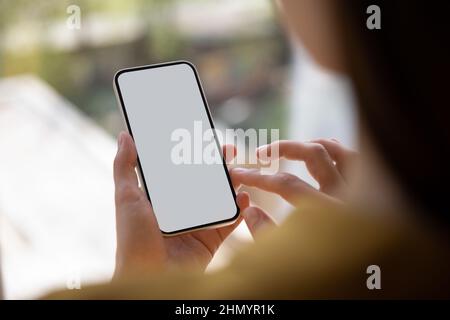 Close up young woman holding smartphone with mock up screen. Stock Photo