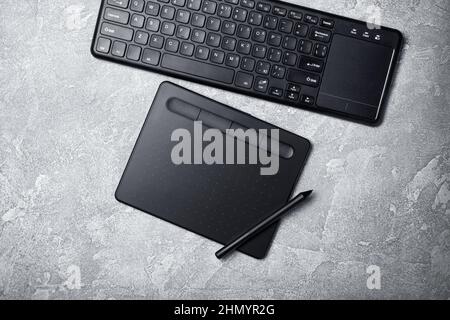 Top view of designer work place with graphics tablet and keyboard on grey concrete background Stock Photo