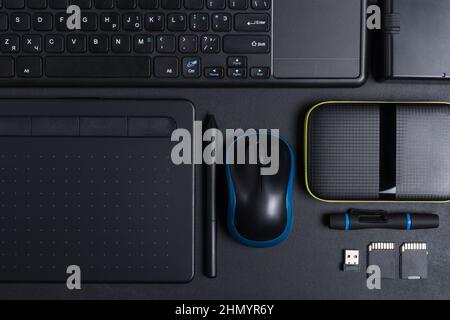 Top view of designer work place with graphics tablet, memory card, keyboard, portable hard drive on black background Stock Photo