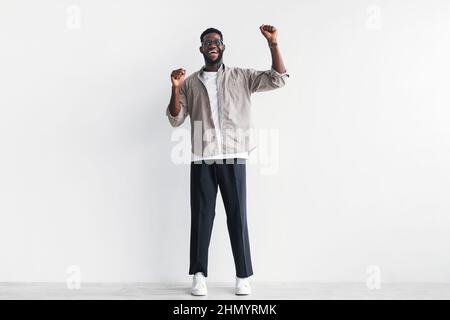 Overjoyed young black man screaming in excitement, gesturing YES with both hands against white studio wall, copy space Stock Photo