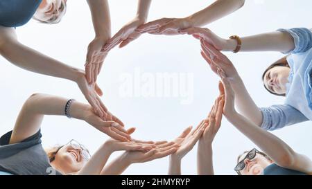 Friends make a circle with their palms against the blue sky. Stock Photo