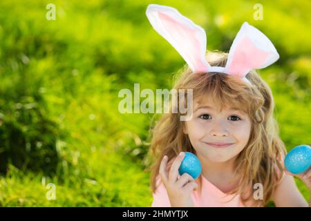 Easter bunny child boy with cute face. Kids hunting easter eggs. Children activity for Easter in nature. Stock Photo