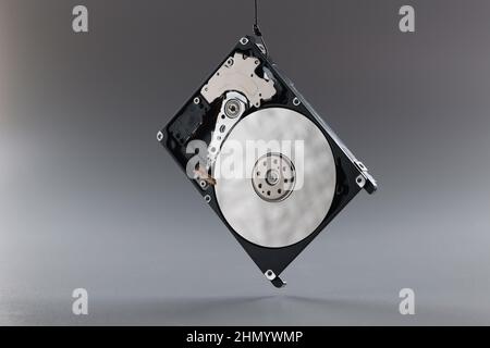 Computer hard disk drive on hook, black hardware disk, memory storage cylinder on grey background Stock Photo