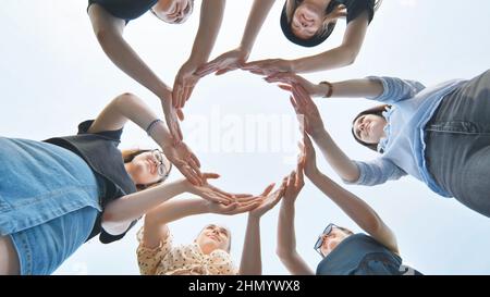 Friends make a circle with their palms against the blue sky. Stock Photo