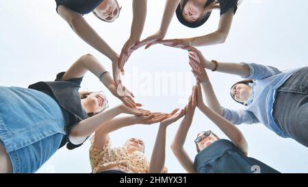 Friends make a circle with their palms against the blue sky. Stock Photo