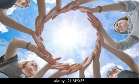 Friends make a circle with their palms against the blue sky. Stock Photo