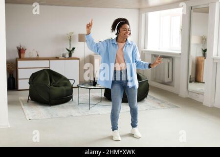 Black lady listening to music and dancing at home Stock Photo