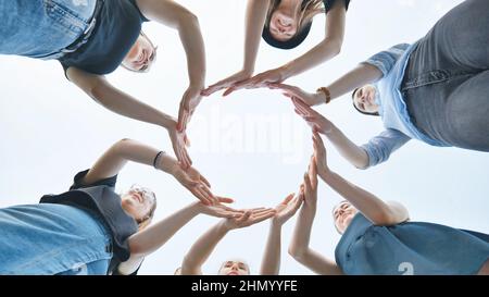 Friends make a circle with their palms against the blue sky. Stock Photo
