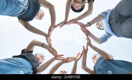 Friends make a circle with their palms against the blue sky. Stock Photo