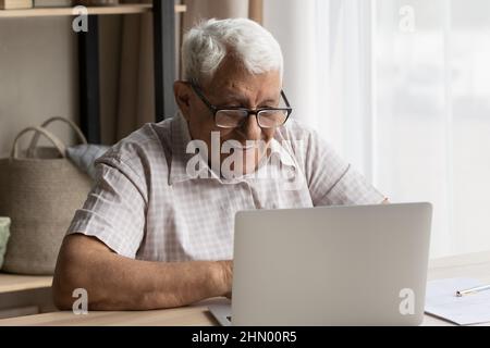 Happy senior older 80s man in glasses using laptop Stock Photo