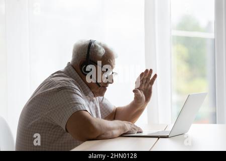 Senior elder 80s lonely man in headphones waving hand Stock Photo