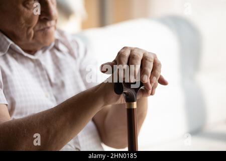 Older man hands leaning on walking cane, holding knob, handle Stock Photo