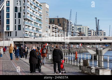 Hamburg, Germany. 12th Feb, 2022. Residents and tourists walk in front of new residential buildings at Versmannkai in Hafencity. Credit: Markus Scholz/picture alliance//dpa/Alamy Live News Stock Photo