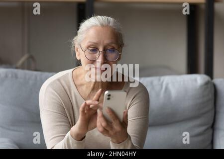 Happy senior woman in glasses reading text message Stock Photo